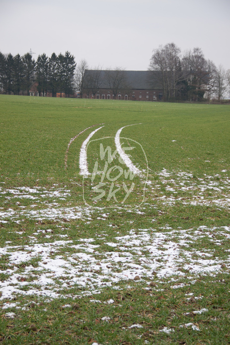 Schneespuren auf grünem Acker